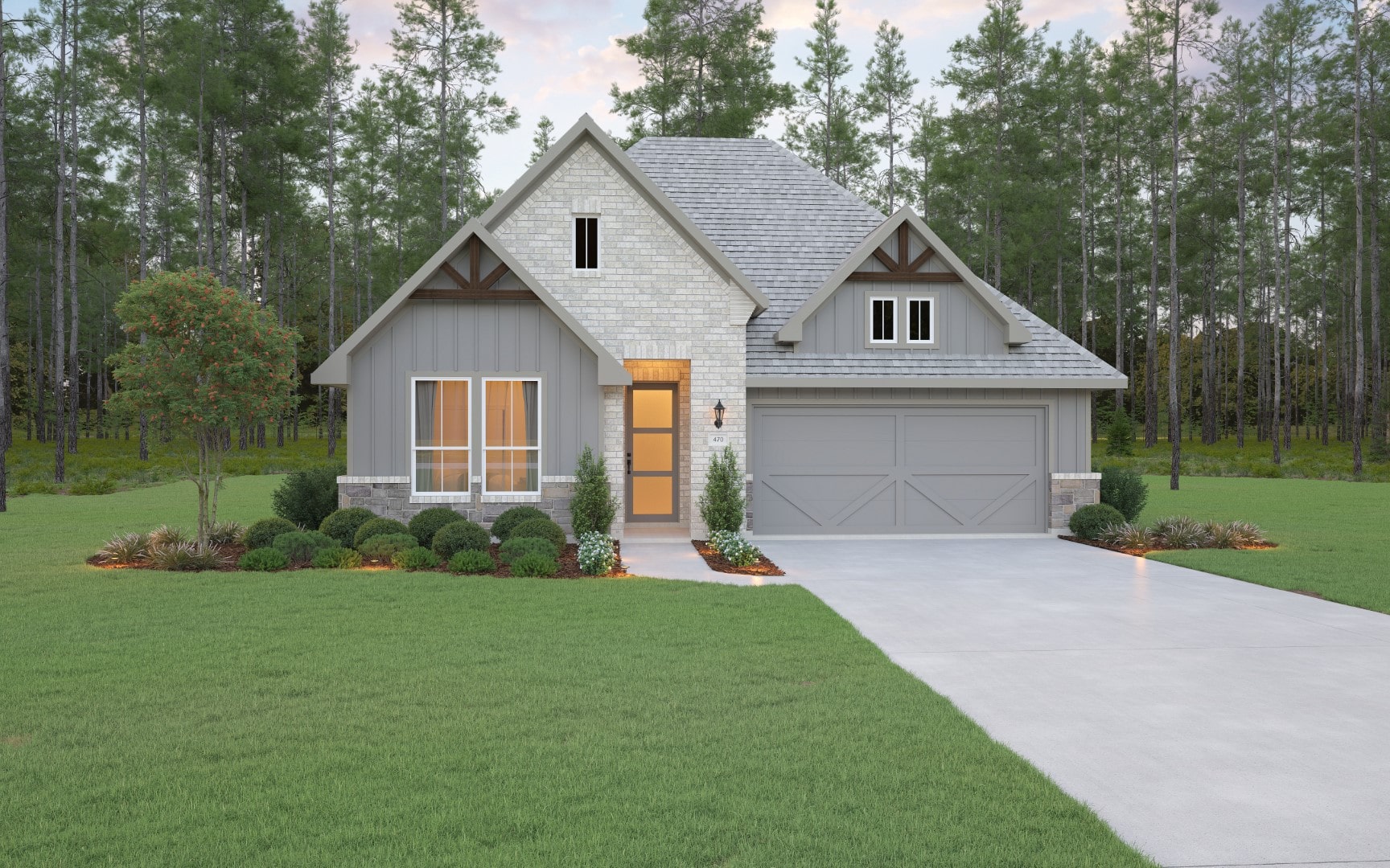 Modern suburban house with a gray exterior, white brick accents, and a two-car garage. It sits on a well-manicured lawn with shrubs, a small tree, and a concrete driveway. Forest trees are visible in the background.